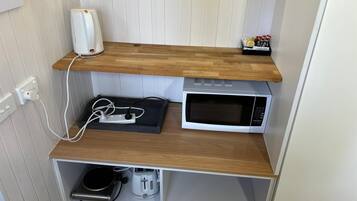 Eine Küche mit Mikrowelle, Toaster und Wasserkocher auf Holzböden.