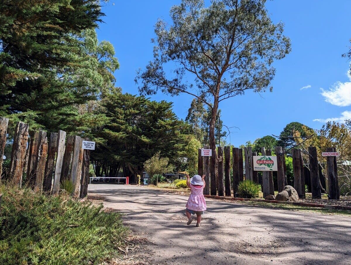 Un camino de tierra que conduce a un portón de madera con letreros, incluyendo uno para Kuil Parks.