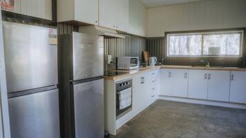 A compact kitchen with a refrigerator, microwave, stove, and sink.