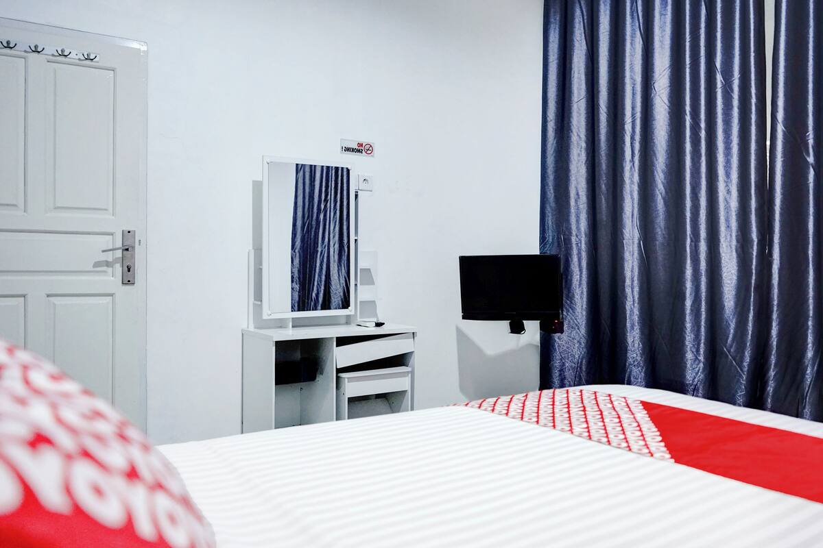Une chambre d’hôtel avec un lit, une télévision, un miroir et une porte.