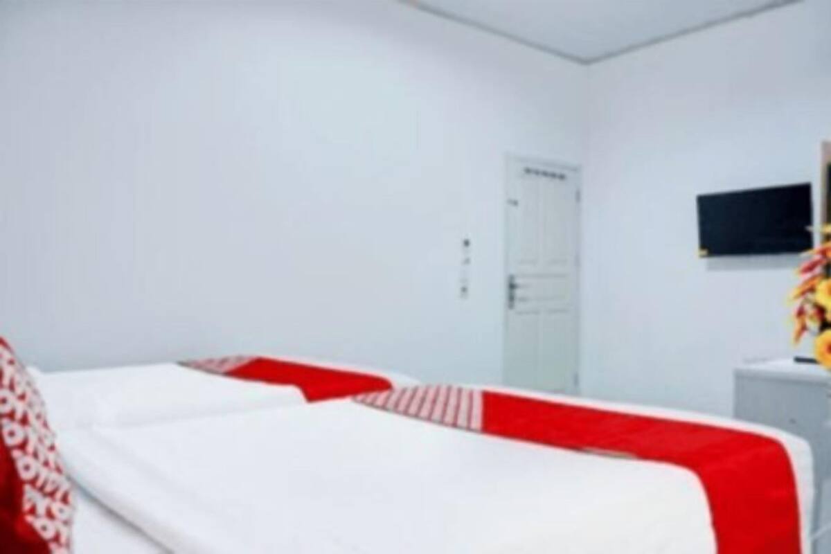 Une chambre d’hôtel avec un lit, un bureau et un téléviseur fixé au mur.