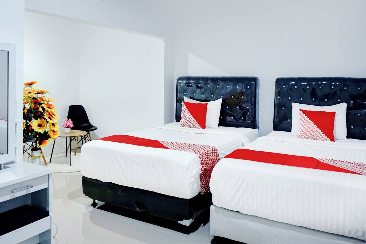 Une chambre d’hôtel avec deux lits, un bureau et une chaise.