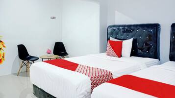A hotel room with two beds, a small table, two chairs, and a wall-mounted sign.