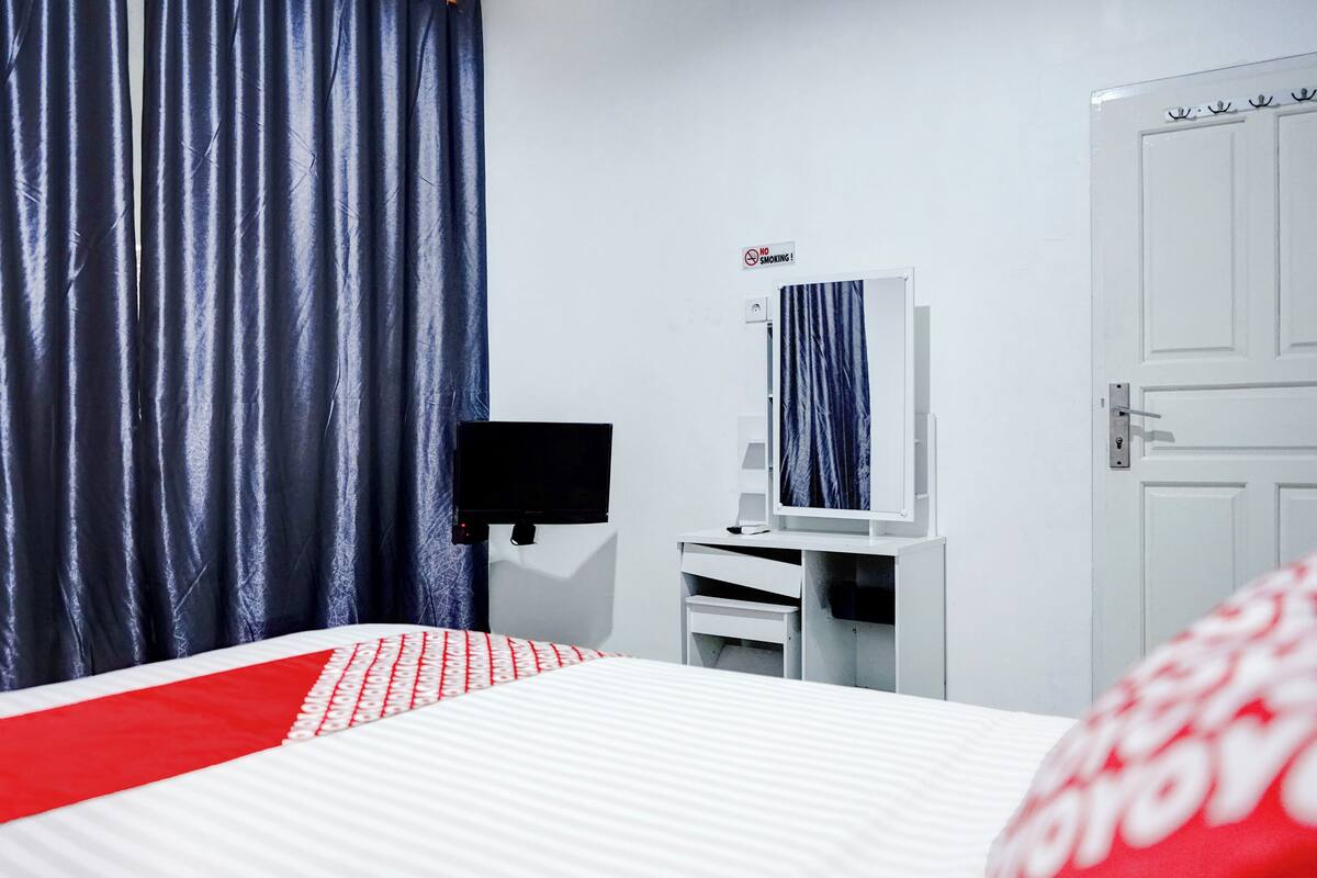 Une chambre d’hôtel équipée d’un lit, d’une télévision, d’un bureau et d’une armoire.