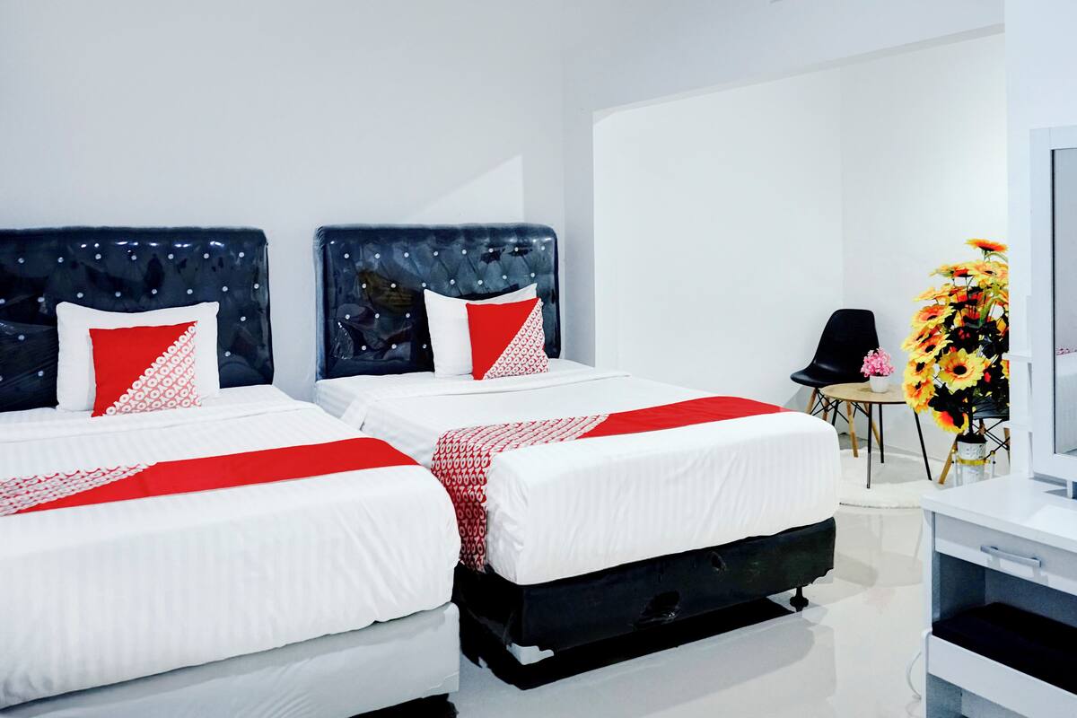 Une chambre d’hôtel moderne équipée de deux lits, d’un bureau et d’une télévision.