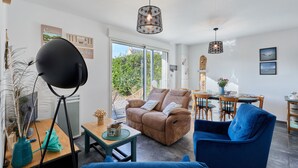 A modern living room with a sofa, a blue armchair, and a dining area with a table and chairs.