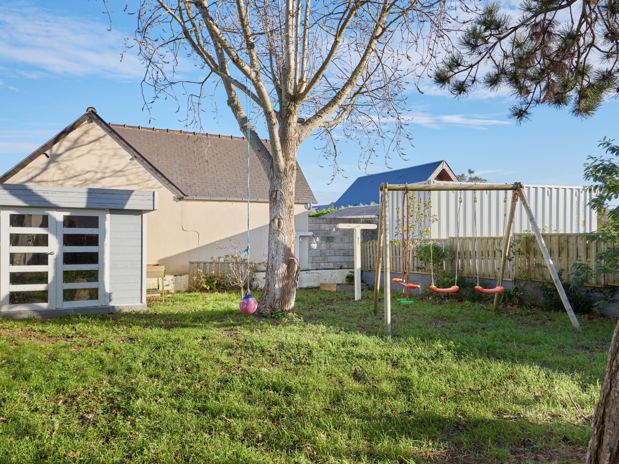 Ein Garten mit Schaukel, Baum und Gartenhaus.