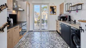 A modern kitchen with a large window, a washing machine, and a coffee machine.