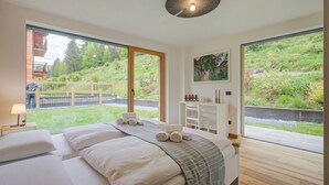 Ein Schlafzimmer mit einem großen Bett, einem Schreibtisch und Blick auf einen Garten.