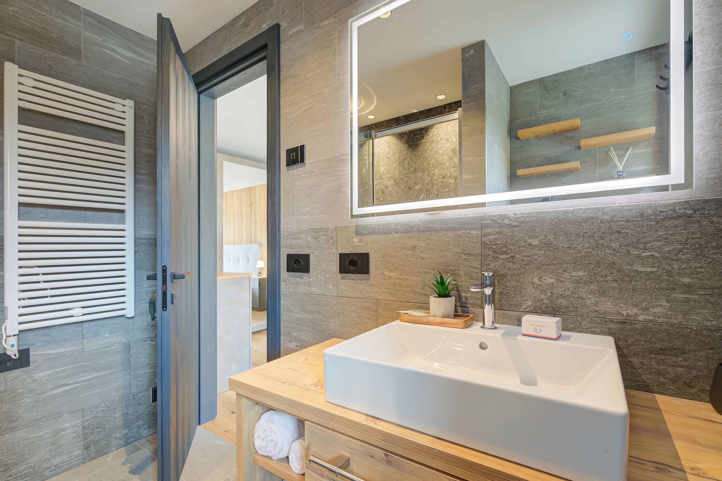 A modern bathroom with a large mirror, a freestanding bathtub, and a wooden vanity.