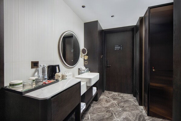 A modern bathroom with two sinks, a large mirror, and a dark wooden door.