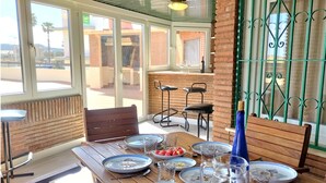 A dining area with a wooden table set for four, featuring blue and white floral plates, clear glassware, and a blue bottle. - Las Pergolas by Interhome (Jávea)
