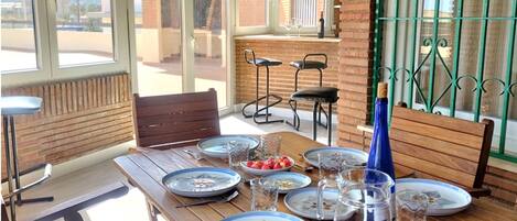 A dining area with a wooden table set for four, featuring blue and white floral plates, clear glassware, and a blue bottle.