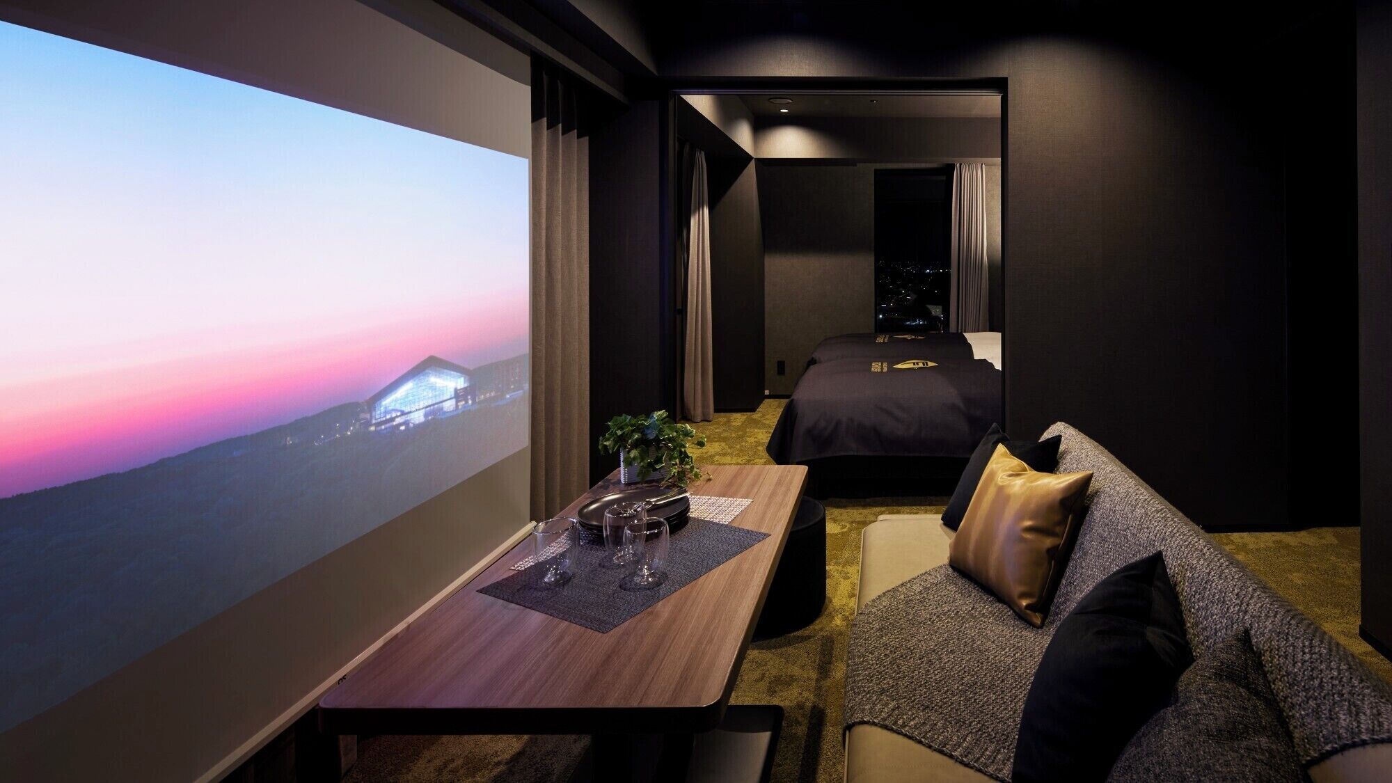 Una habitación de hotel moderna con un ventanal grande, una mesa de comedor, un sofá y una cama.