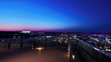 Paisagem urbana noturna com vista para um estádio e edifícios iluminados.