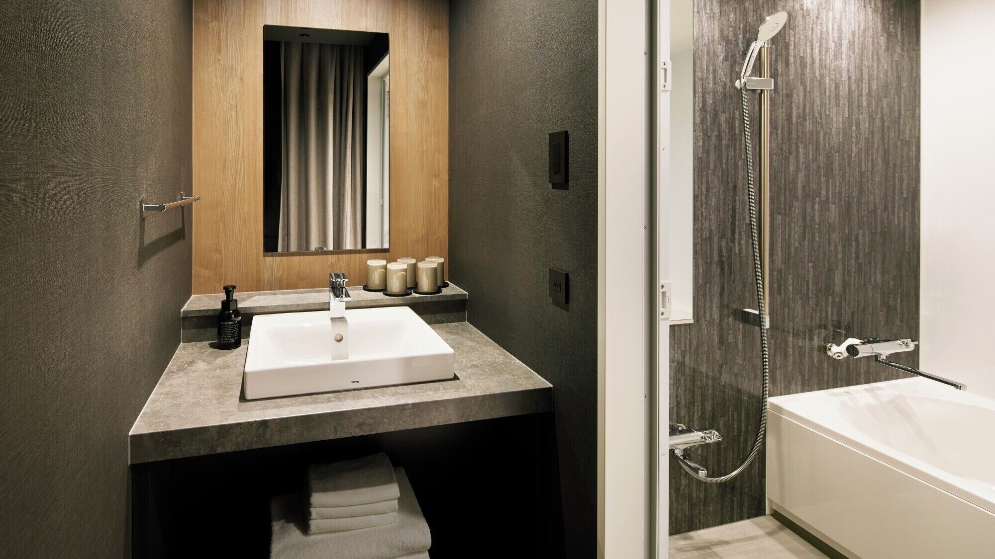 A modern bathroom with a large sink, a mirror, a shower, and a towel rack.