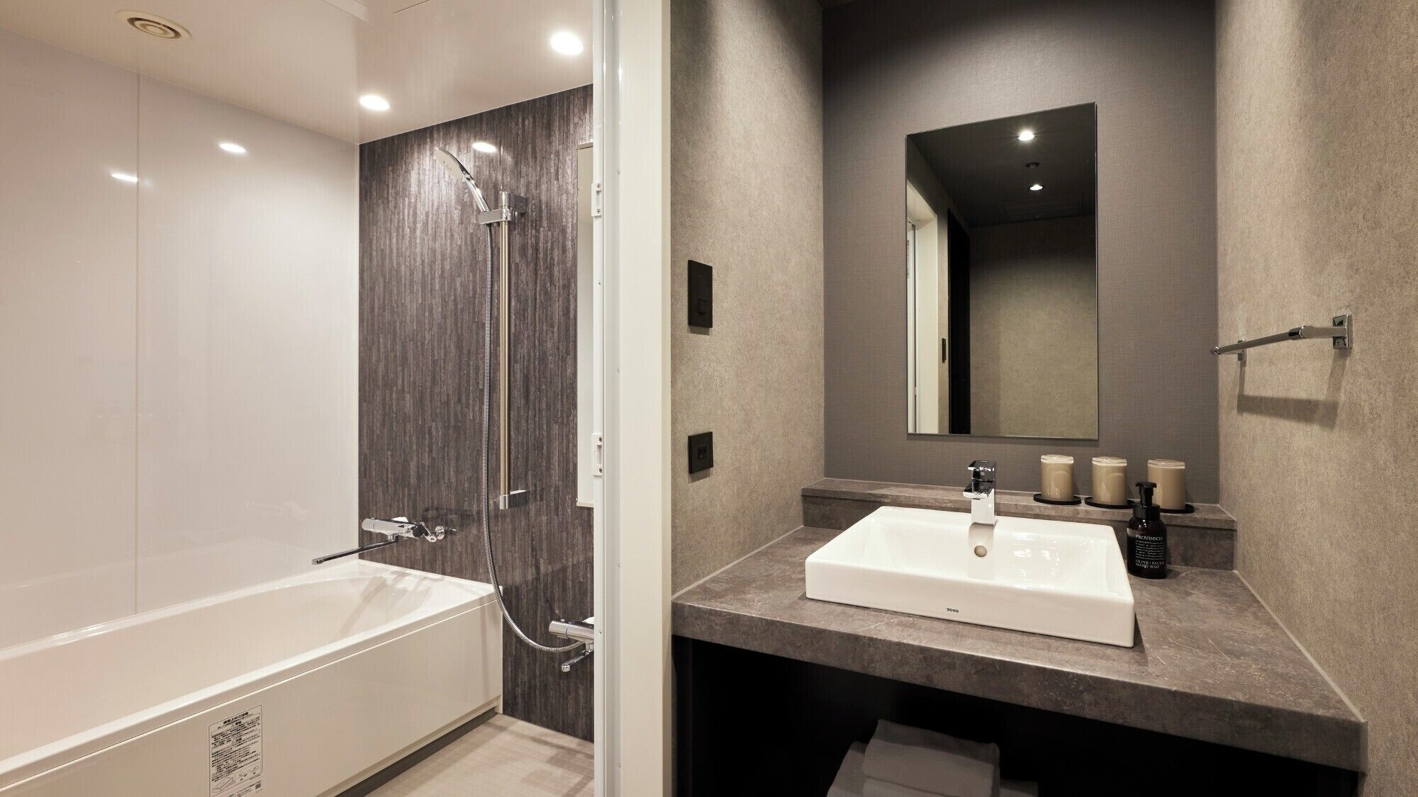 A modern bathroom with a bathtub, a shower with a rain showerhead, a large mirror, and a vanity with a sink and toiletries.