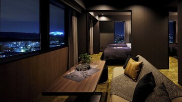 Quarto de hotel moderno com vista para a cidade, área de refeições e quarto separado.