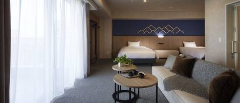 A modern hotel room with a bed, a sofa, a small table with a plant, and a decorative wall.