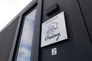 Une pancarte sur le mur d’un immeuble indique un service géré par « Tiny Away », avec une icône représentant une maison.