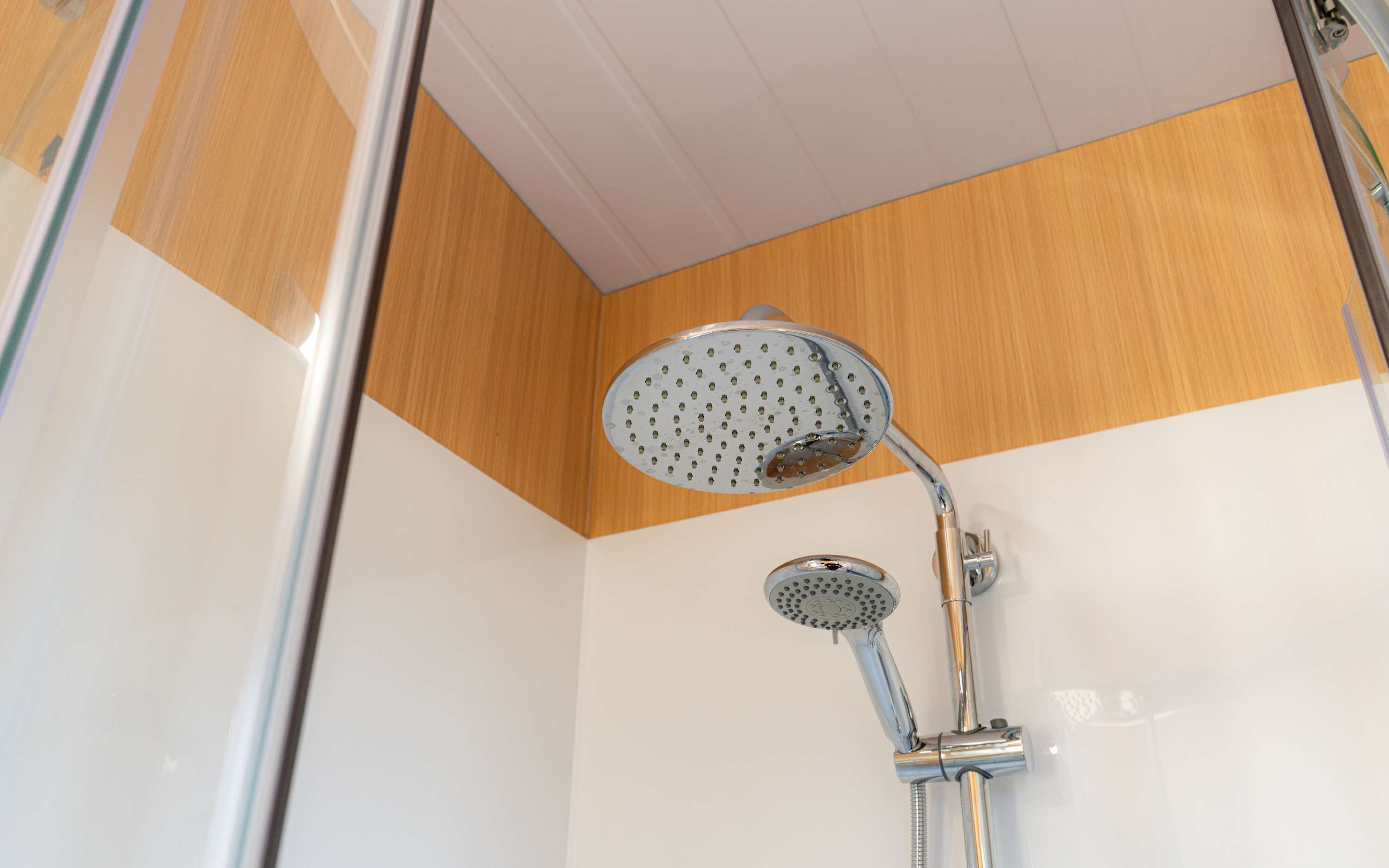 Eine Dusche mit Duschbrause im Handstück und fest installierter Duschbrause, beide mit mehreren Strahldüsen.
