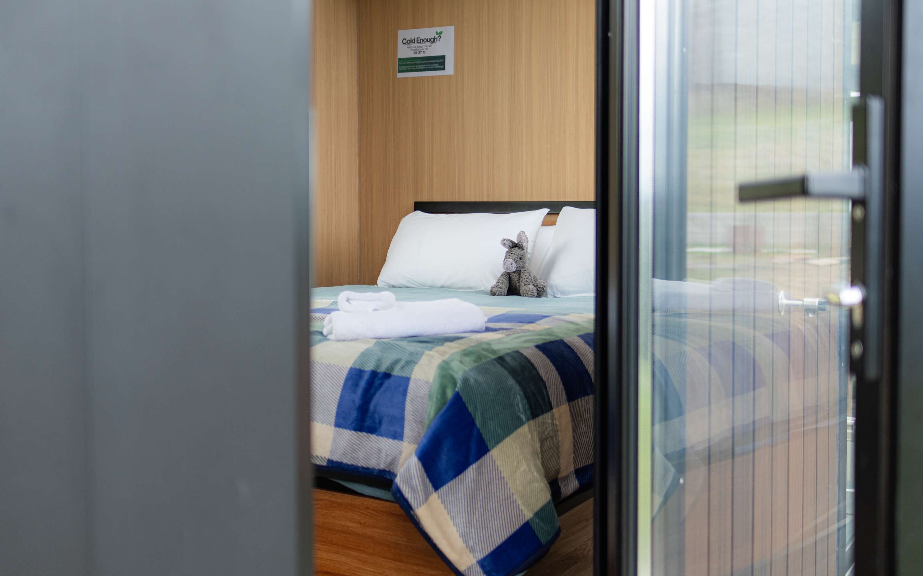 Quarto de hotel com uma cama, um brinquedo de pelúcia e uma placa na parede.