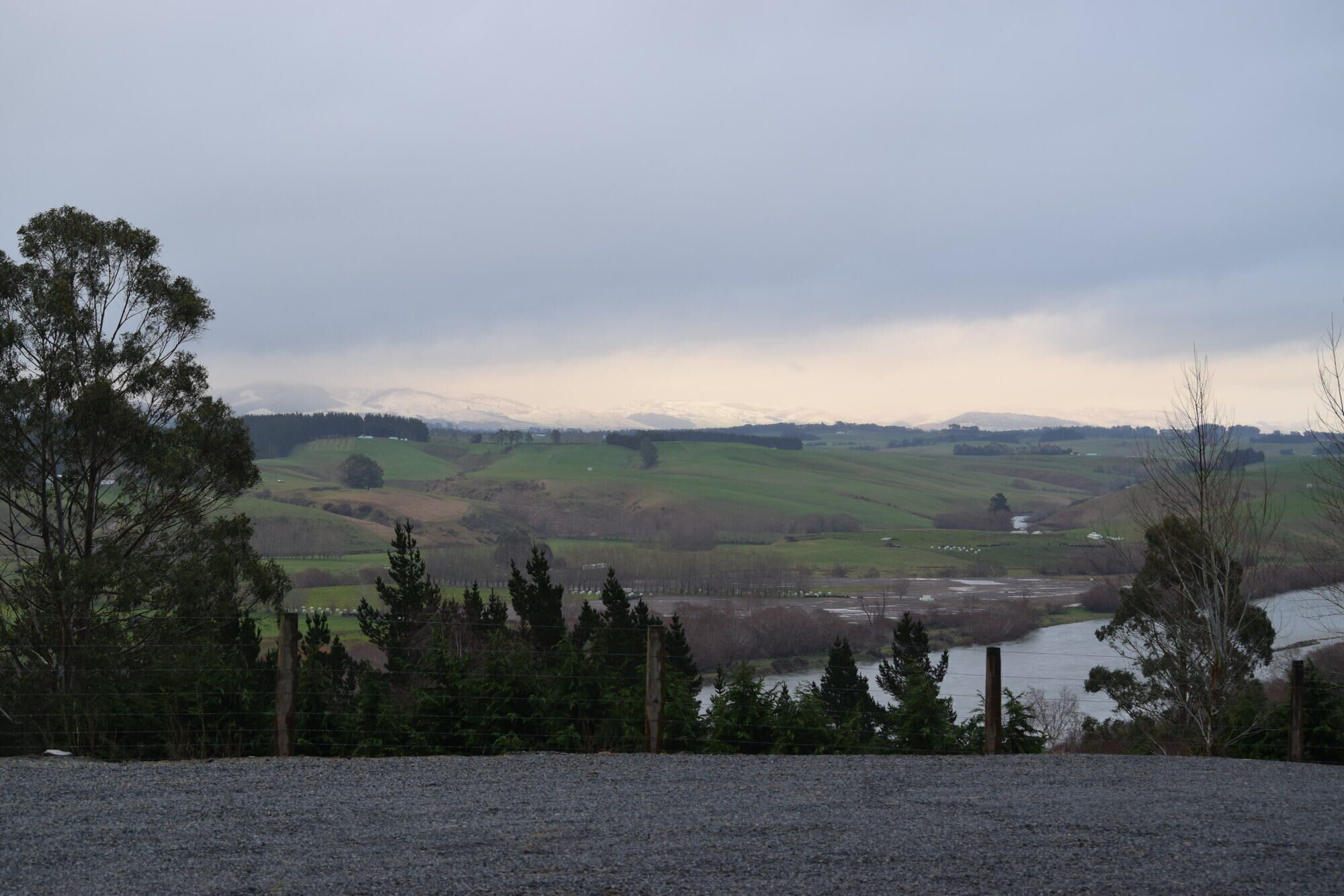 A rural landscape with rolling hills, a river, and sparse vegetation.