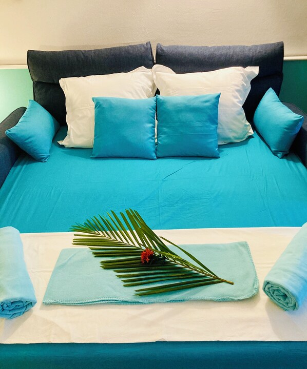 A neatly made bed with blue bedding, a white pillow, and a blue towel. - Tikazadaph, charming, exotic and romantic stay by the sea (2-4p.) (Sainte-Anne)