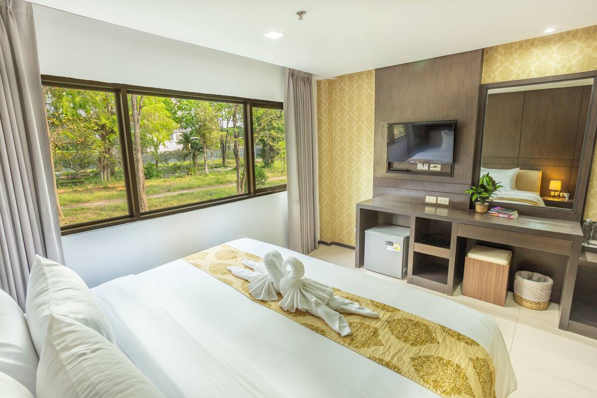 Une chambre d’hôtel avec un grand lit, une télévision, un bureau et une vue sur l’extérieur.