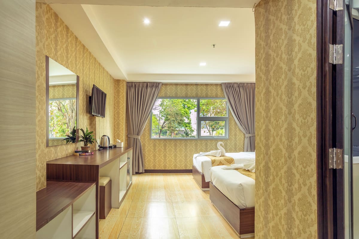 Une chambre d’hôtel avec un bureau en bois, un lit, une télévision et une fenêtre avec des rideaux.