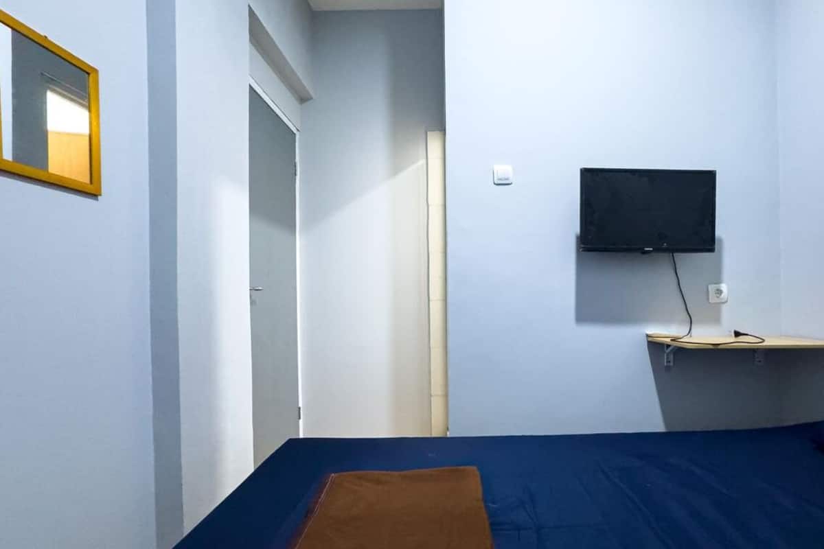 A bedroom with a bed, a TV mounted on the wall, and a bedside table.