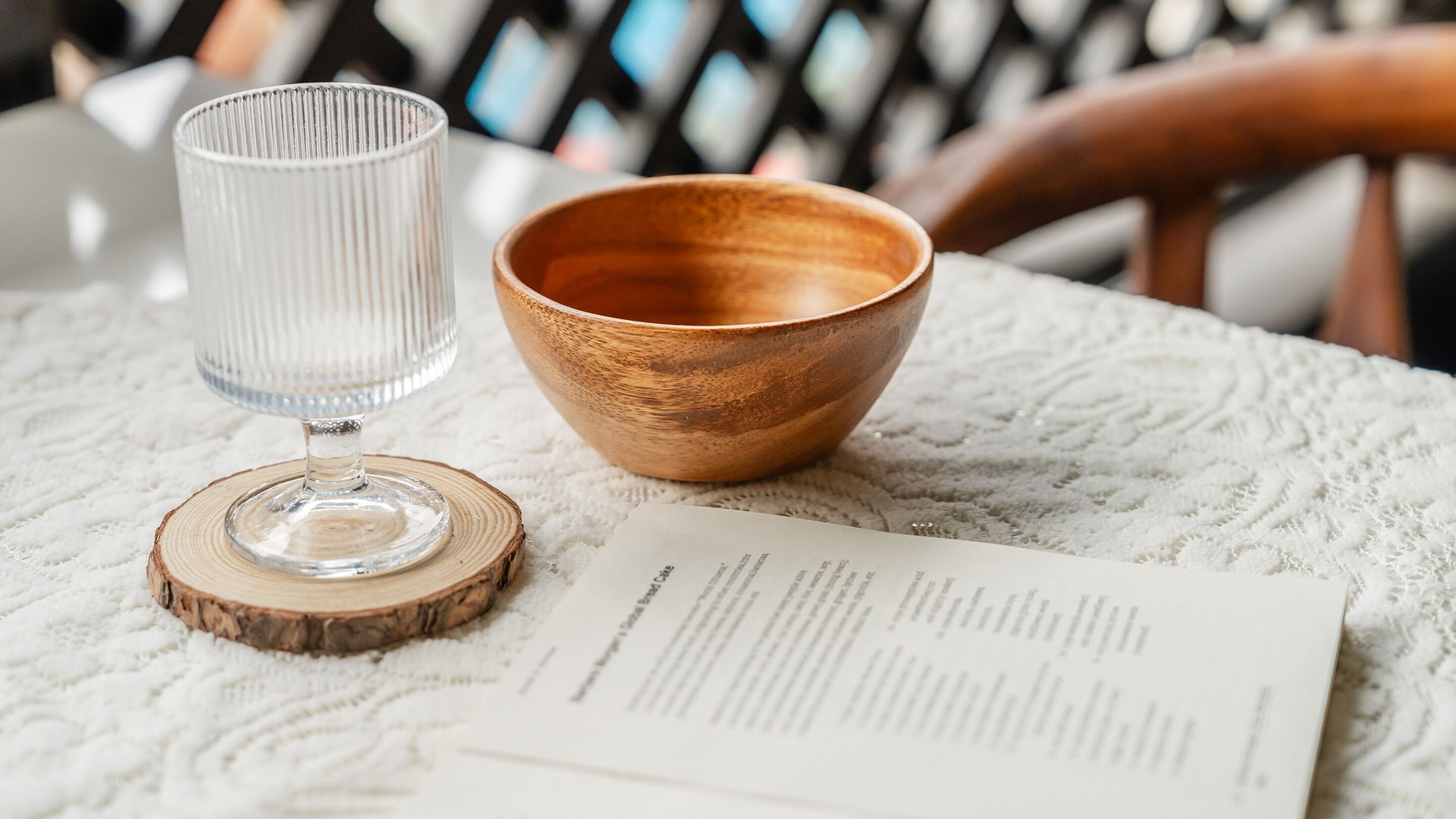 A wooden bowl and a glass on a table with a menu.
