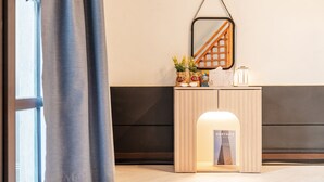 A modern reception area with a wooden console table, a framed book titled 'PORTAITS', and a hanging mirror. - Gangchon Afternoon Pool Villa Pension (Chuncheon)