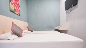 A hotel room with two beds, a bedside table with a phone, and a wall-mounted TV. - Hotel O Panakukkang Near Mall Panakkukang Formerly Hawai Inn (Makassar)
