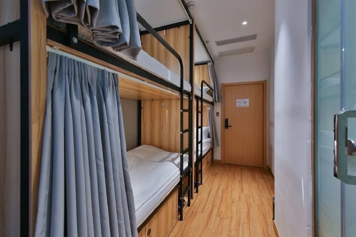 A narrow room with bunk beds, wooden flooring, and a door.