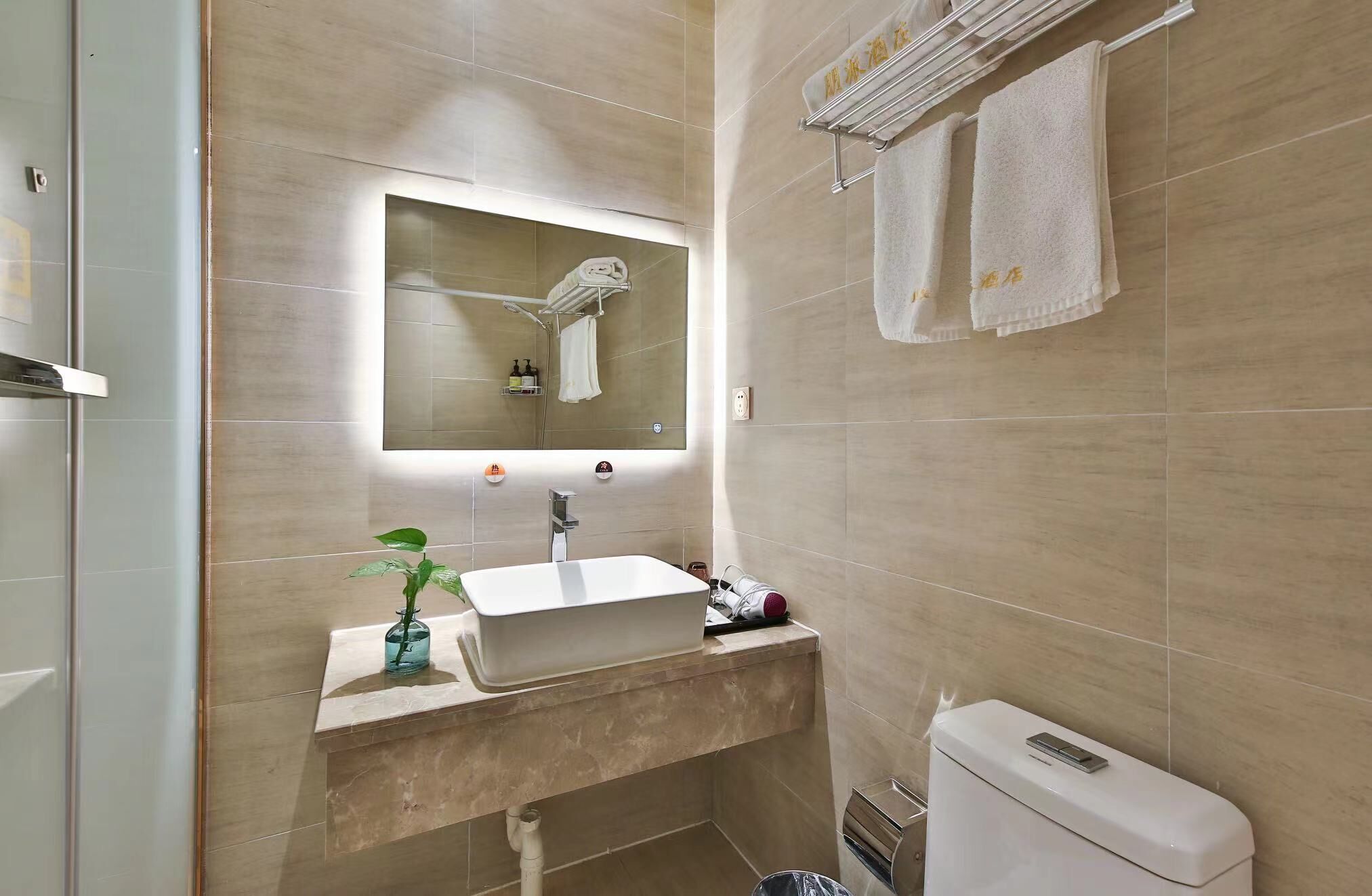 A modern bathroom with a large mirror, a sink, a toilet, and a towel rack.