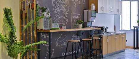 A modern kitchen with a chalkboard wall, bar stools, and a coffee machine.