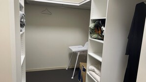 A walk-in closet with a white chair, shelves, and hanging space.