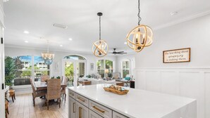 A spacious kitchen with a large island, white cabinetry, and a view of the outdoors.