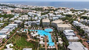 A resort with multiple buildings, a central pool, and a view of the ocean.