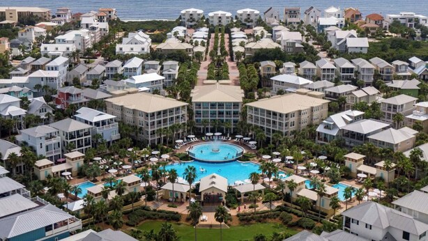 A resort with multiple buildings, a central pool, and a view of the ocean.