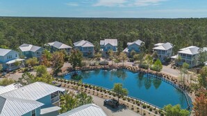 A resort with multiple buildings, a central swimming pool, and a forested backdrop.
