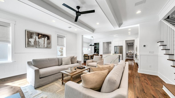 A spacious living room with a large sofa set, a coffee table, and a ceiling fan.