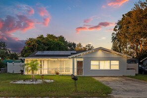 A single-story house with a garage, a small front yard, and a clear sky. - 4BR | Screened Pool | Next to Park | 10 Min Indian Rocks Beach | Sleeps 10 (Largo)