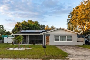 A single-story house with a front porch, a garage, and a small front yard. - 4BR | Screened Pool | Next to Park | 10 Min Indian Rocks Beach | Sleeps 10 (Largo)