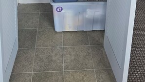 A storage closet with shelves holding dishes, glasses, and kitchenware. - Cozy Cove Ohope Beach (Ohope)