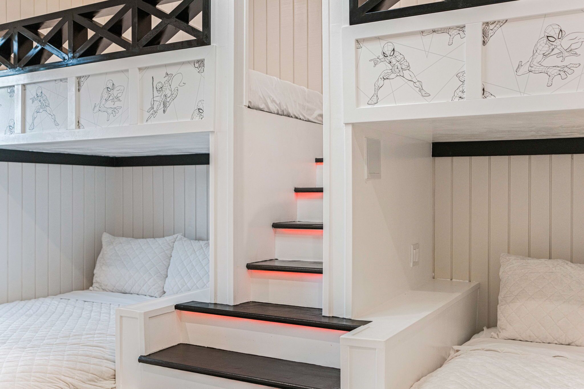 A bunk bed with a white and black color scheme, featuring a headboard with a geometric design and a shelf with red lighting.