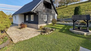 Una casa a due piani con facciata scura, rifiniture bianche e tetto a forte pendenza.