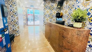 A reception area with a marble counter, patterned walls, and a potted plant. - Hou Kong Boutique Hostel (Macau)
