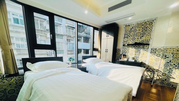 A hotel room with two beds, a large window, a minibar, and patterned tiles. - Hou Kong Boutique Hostel (Macau)